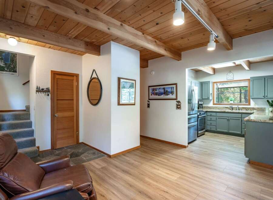 Step into this charming cabin-style home featuring a warm and inviting living space with a cozy leather armchair and a rustic wooden ceiling.