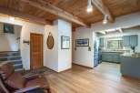 Step into this charming cabin-style home featuring a warm and inviting living space with a cozy leather armchair and a rustic wooden ceiling.
