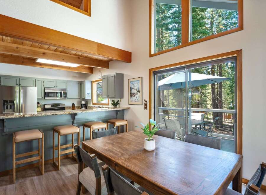 Experience mountain living in this charming dining and kitchen area, featuring a spacious wooden dining table perfect for gatherings and a well-equipped kitchen with ample counter space and bar seating.