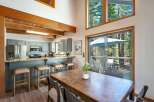 Experience mountain living in this charming dining and kitchen area, featuring a spacious wooden dining table perfect for gatherings and a well-equipped kitchen with ample counter space and bar seating.