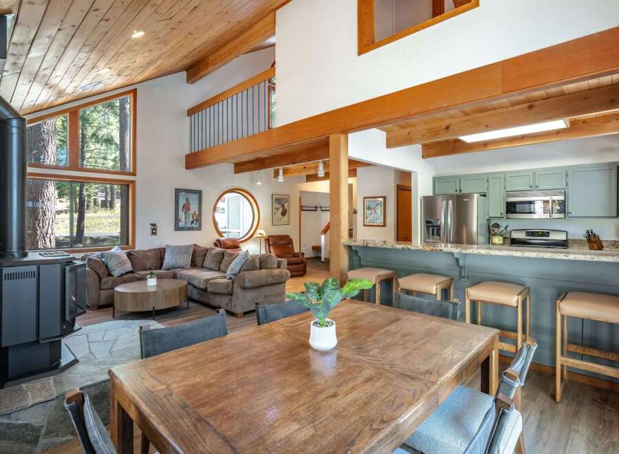 Experience cozy living in this charming mountain retreat, featuring a spacious open-concept living area with a striking wood-burning stove and vaulted, wood-paneled ceilings.