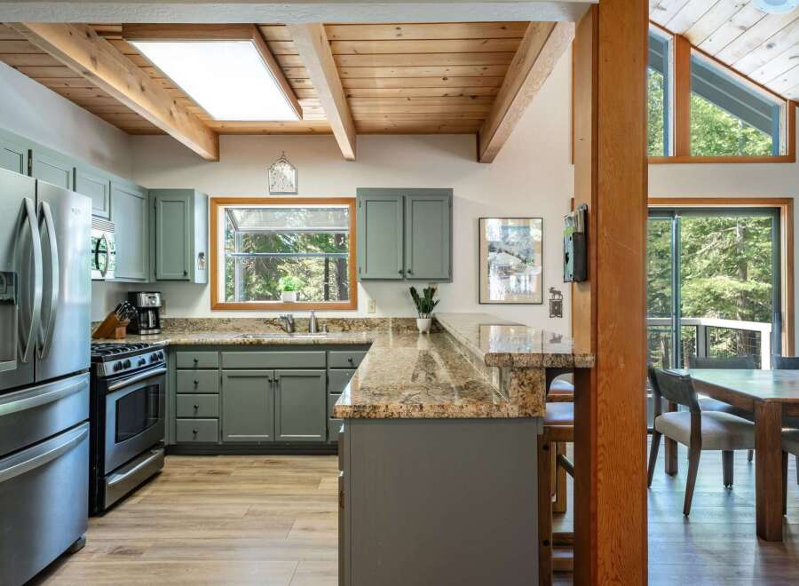 Experience rustic charm in this spacious kitchen featuring sleek grey cabinetry and a stunning granite countertop breakfast bar.