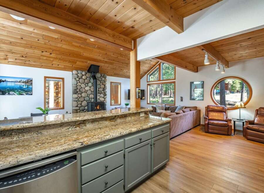 Experience rustic charm and modern comfort in this inviting living space, featuring a stunning stone fireplace and a vaulted wood-paneled ceiling.