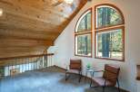 Ascend to this charming loft space, featuring a vaulted wood-paneled ceiling and a stunning arched window that frames picturesque forest views.