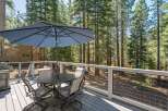Enjoy outdoor dining and relaxation on this spacious deck, complete with a table, chairs, and a large umbrella for shade.