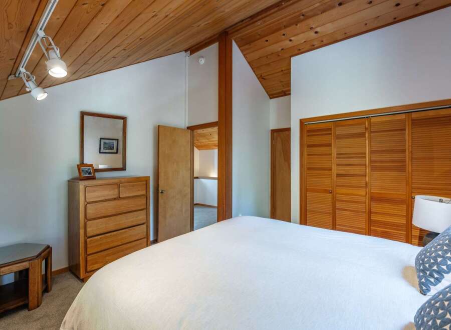 Discover this charming bedroom featuring a vaulted wood-paneled ceiling and ample natural light.