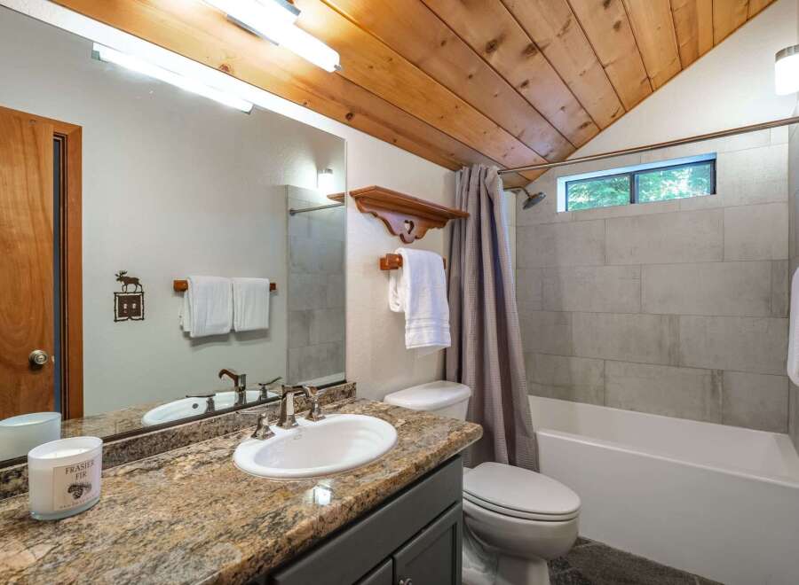 This charming bathroom features a granite countertop vanity with a white sink and modern chrome fixtures.