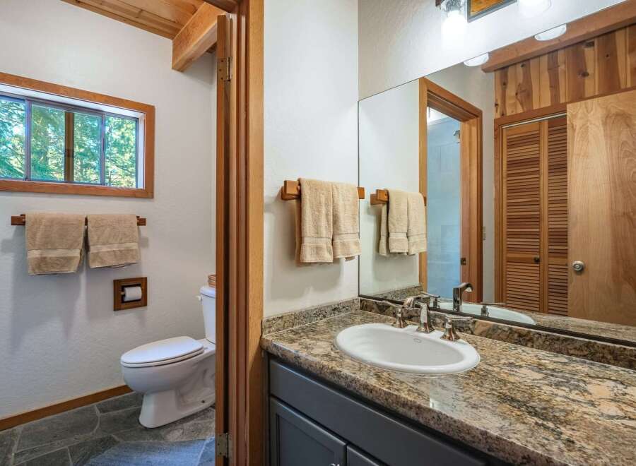This bathroom features a charming rustic design with warm wood accents and natural stone flooring.