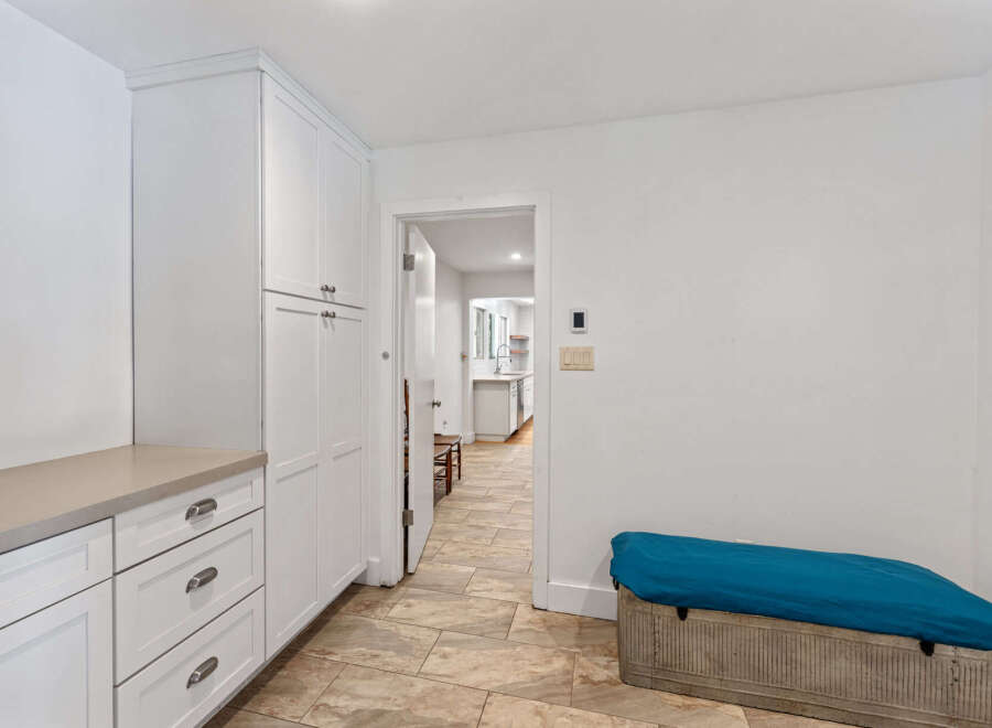 Discover ample storage solutions in this home, featuring a wall of custom white cabinetry and a sleek countertop perfect for organization.