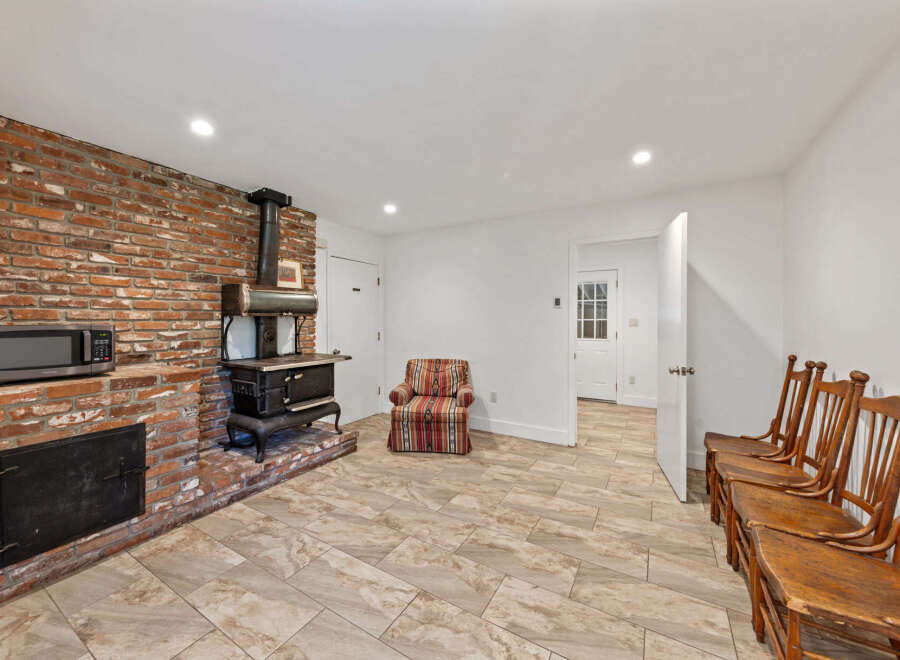 Discover rustic charm in this unique living space, featuring a striking exposed brick wall with a vintage wood-burning stove and a convenient microwave.