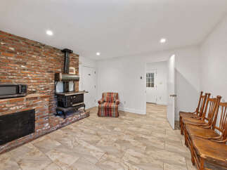 Discover rustic charm in this unique living space, featuring a striking exposed brick wall with a vintage wood-burning stove and a convenient microwave.