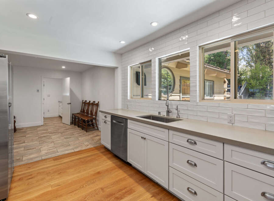 This spacious kitchen boasts modern white subway tile backsplash and sleek concrete countertops, complemented by ample cabinet storage and a stainless steel dishwasher.