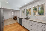 This spacious kitchen boasts modern white subway tile backsplash and sleek concrete countertops, complemented by ample cabinet storage and a stainless steel dishwasher.