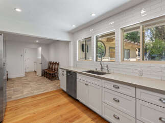 This spacious kitchen boasts modern white subway tile backsplash and sleek concrete countertops, complemented by ample cabinet storage and a stainless steel dishwasher.