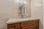 This bathroom vanity features a light beige subway tile backsplash that complements the natural stone countertop.