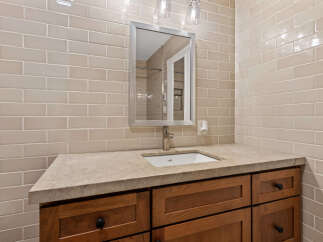 This bathroom vanity features a light beige subway tile backsplash that complements the natural stone countertop.