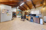 Discover a versatile space with a rustic charm, featuring a vaulted wood-paneled ceiling and ample natural light.