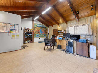 Discover a versatile space with a rustic charm, featuring a vaulted wood-paneled ceiling and ample natural light.