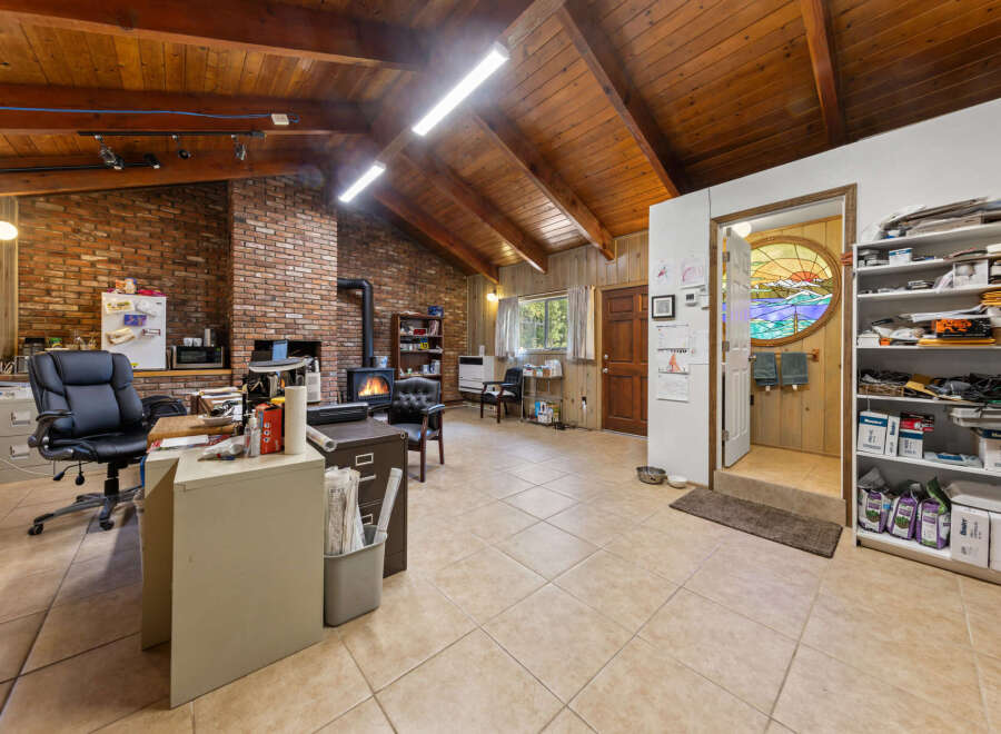 Discover a unique living space with a rustic charm, featuring a soaring wood-beamed ceiling and exposed brick walls.
