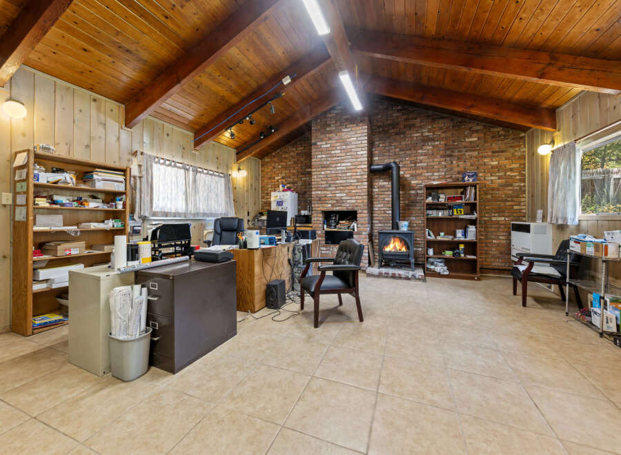 Discover a spacious and inviting office space featuring a cozy brick fireplace with a wood-burning stove, perfect for creating a warm atmosphere.