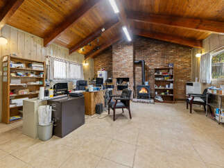 Discover a spacious and inviting office space featuring a cozy brick fireplace with a wood-burning stove, perfect for creating a warm atmosphere.