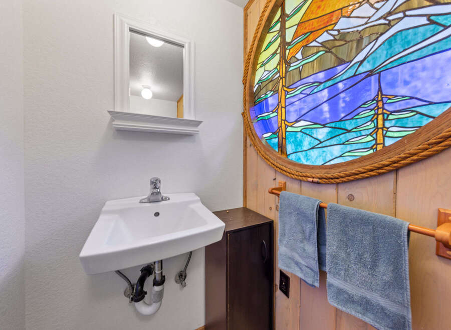 Discover a charming bathroom featuring a unique stained-glass window that adds a touch of artistry and color to the space.
