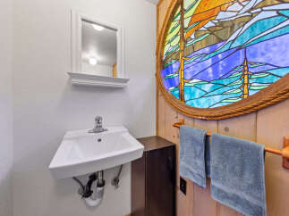 Discover a charming bathroom featuring a unique stained-glass window that adds a touch of artistry and color to the space.