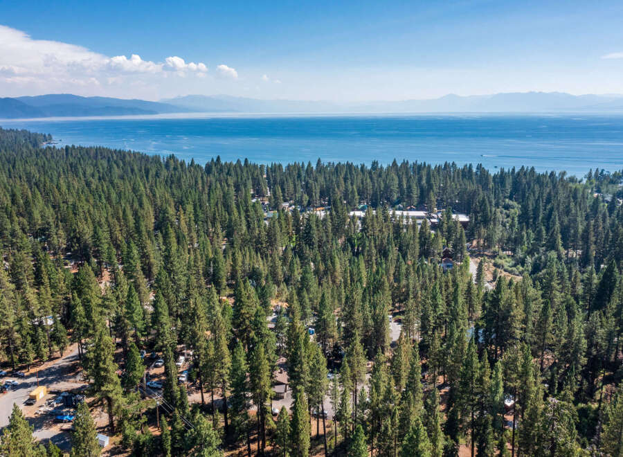 Experience the serene beauty of Lake Tahoe with this stunning aerial view of a property nestled amidst a dense pine forest.