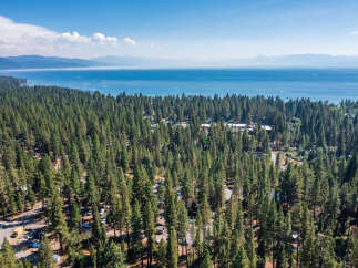 Experience the serene beauty of Lake Tahoe with this stunning aerial view of a property nestled amidst a dense pine forest.