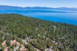 Nestled amidst a dense forest of tall pine trees, this property offers a serene retreat with stunning views of a vast, blue lake and distant mountains.