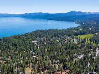 Discover this stunning aerial view of a lakeside community nestled amidst a dense pine forest.