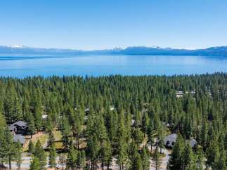 Experience breathtaking lake and mountain views from this stunning property nestled amongst a dense forest of pine trees.