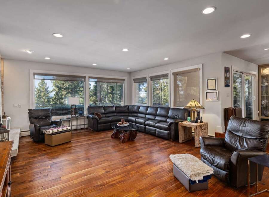 Experience breathtaking mountain views from this spacious living room, featuring a large sectional sofa and comfortable leather recliners.