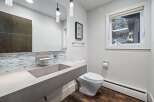 This modern bathroom features a sleek concrete sink and vanity, complemented by a striking mosaic tile backsplash.