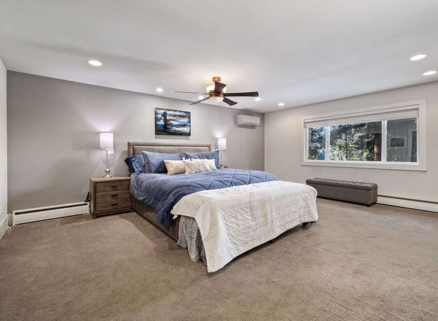 Experience ultimate comfort in this spacious master bedroom, featuring a luxurious king-sized bed adorned with plush blue bedding.
