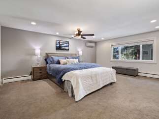 Experience ultimate comfort in this spacious master bedroom, featuring a luxurious king-sized bed adorned with plush blue bedding.