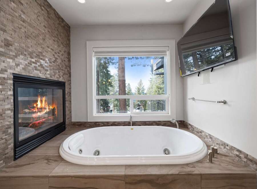 Indulge in ultimate relaxation in this luxurious bathroom, featuring a stunning stone-tiled fireplace and a deep soaking tub.