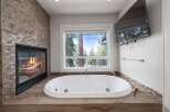 Indulge in ultimate relaxation in this luxurious bathroom, featuring a stunning stone-tiled fireplace and a deep soaking tub.