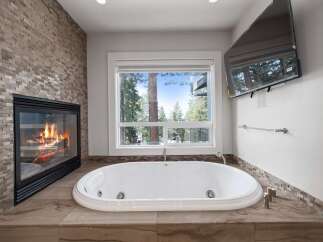 Indulge in ultimate relaxation in this luxurious bathroom, featuring a stunning stone-tiled fireplace and a deep soaking tub.