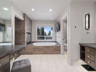 Indulge in luxury in this stunning master bathroom, featuring a deep soaking tub with a picturesque view of the surrounding trees.