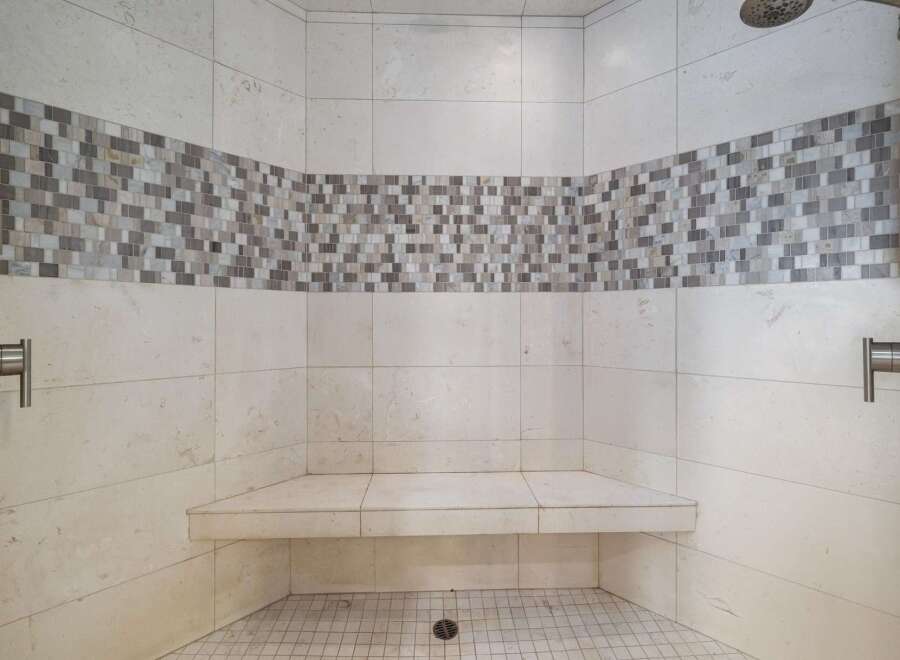 Experience luxury and comfort in this beautifully designed shower featuring a built-in bench and elegant mosaic tile accent.