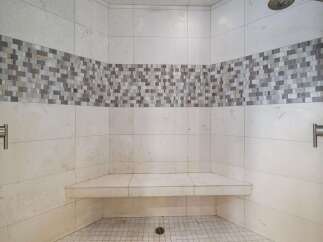 Experience luxury and comfort in this beautifully designed shower featuring a built-in bench and elegant mosaic tile accent.