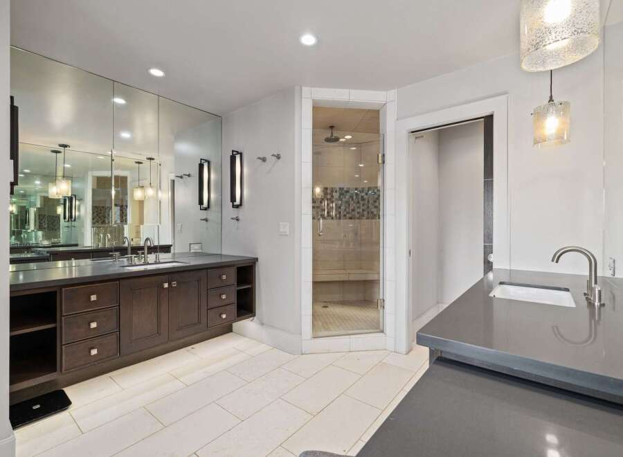 Experience luxury in this spacious bathroom featuring a large vanity with ample storage and a wall of mirrors.