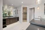 Experience luxury in this spacious bathroom featuring a large vanity with ample storage and a wall of mirrors.