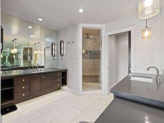 Experience luxury in this spacious bathroom featuring a large vanity with ample storage and a wall of mirrors.