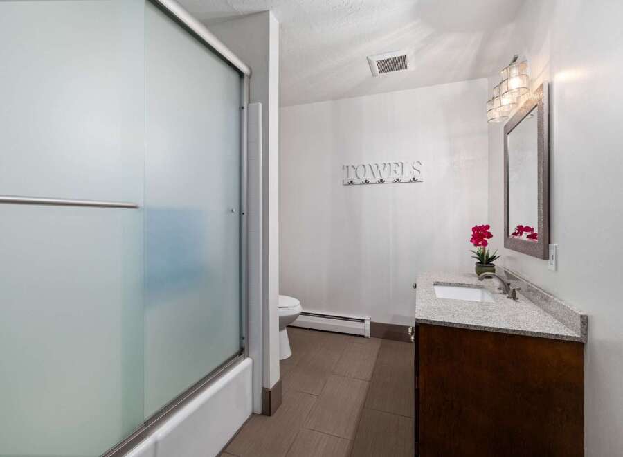 This bathroom features a frosted glass shower door and a clean white bathtub.