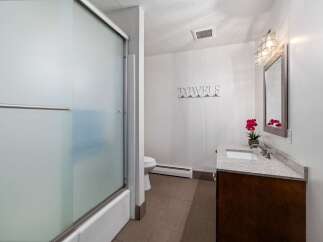 This bathroom features a frosted glass shower door and a clean white bathtub.
