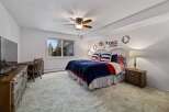 This charming bedroom features a comfortable queen-size bed adorned with patriotic-themed bedding, including striped pillows and a navy blue plush throw.