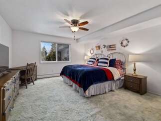 This charming bedroom features a comfortable queen-size bed adorned with patriotic-themed bedding, including striped pillows and a navy blue plush throw.