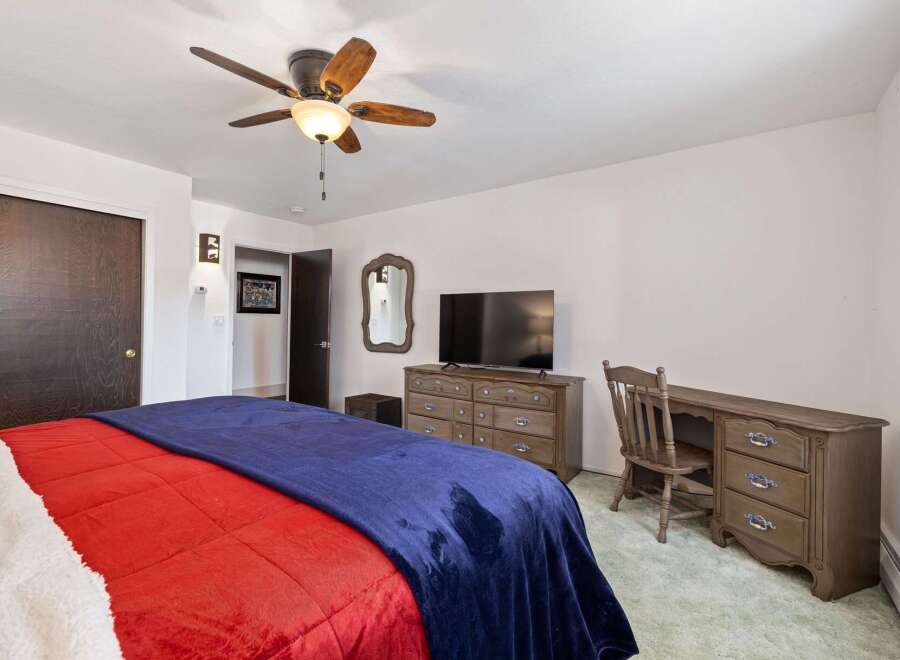 This cozy bedroom features a comfortable bed with vibrant red and blue bedding, perfect for relaxation.